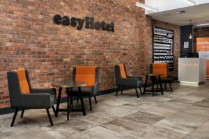 un grupo de mesas y sillas contra una pared de ladrillo en easyHotel Sheffield en Sheffield