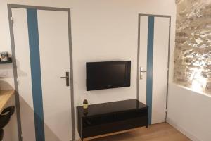 ein Wohnzimmer mit einem TV und eine Wand mit einer Tür in der Unterkunft Atelier du 7 in Bouzigues