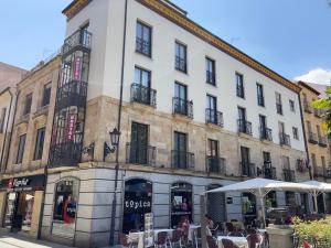 a large building with tables and umbrellas in front of it at Hostal Concejo in Salamanca