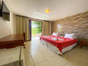 a bedroom with a bed with a red blanket at Pousada Mãe Natureza in Pipa