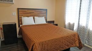 sypialnia z dużym łóżkiem z pomarańczową narzutą w obiekcie Holly Crest Hotel - Los Angeles, LAX Airport w mieście Inglewood