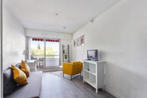 a living room with a yellow chair and a television at Studio with terrace close to the Prado beach in Marseille Welkeys in Marseille