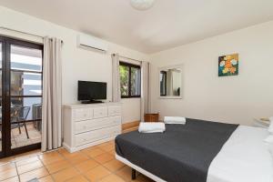 a bedroom with a bed and a television and a balcony at Algarve Luxury Experience - Situated within the Pinecliffs Resort in Albufeira