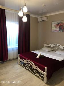 a bedroom with a large bed with a red curtain at Hotel Barhat Аktobe in Aktobe