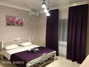a bedroom with a bed with purple curtains and a window at Hotel Barhat Аktobe in Aktobe