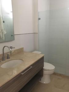 a bathroom with a sink and a toilet and a mirror at Morros Suites Apartamentos in Cartagena de Indias