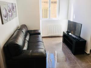 ラ・トゥール・デュ・パンにあるAppartement la Gareのリビングルーム(革張りのソファ、薄型テレビ付)