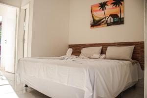 uma cama branca num quarto com uma fotografia na parede em POUSADA TEIXEIRA em Barreirinhas
