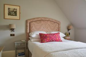 ein Schlafzimmer mit einem Bett mit einem rosa Kissen darauf in der Unterkunft The White House in Burnham Market