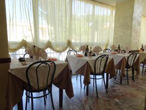 una sala da pranzo con tavoli e sedie con tende bianche di Hotel Jumbo a Rimini