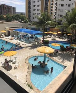 a group of people in a swimming pool with umbrellas at APARTAMENTO JARDINS DAS THERMAS CALDAS NOVA in Caldas Novas