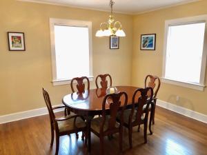 a dining room with a table and chairs and two windows at Calypso Pensacola in East Hill Neighborhood ! in Pensacola