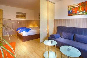 ein Wohnzimmer mit einem blauen Sofa und einem Bett in der Unterkunft H&H Apartment im Herzen der Stadt Nr 29-Henning mit Balkon in Greifswald