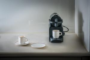 two cups of coffee sitting on a counter with a tea kettle at Skajado Holiday Apartments in Stalís