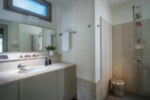 a bathroom with a sink and a mirror and a shower at Skajado Holiday Apartments in Stalís