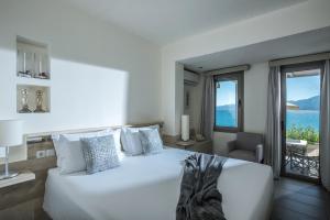 a bedroom with a white bed with a view of the ocean at Skajado Holiday Apartments in Stalís