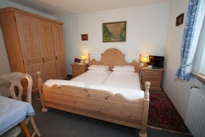 ein Schlafzimmer mit einem großen Holzbett mit weißer Bettwäsche in der Unterkunft Haus Höllental in Garmisch-Partenkirchen