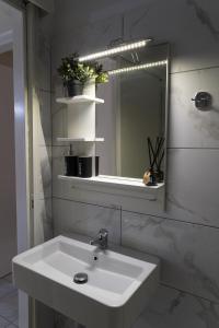 een badkamer met een witte wastafel en een spiegel bij Melanthi Apartment in Keramotí