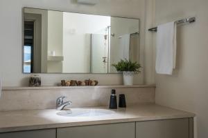 a bathroom with a sink and a large mirror at Skajado Holiday Apartments in Stalís