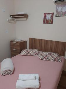 a bedroom with a pink bed with towels on it at Varandas do Atalaia Suítes in Arraial do Cabo