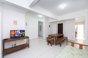 sala de estar con TV y mesa en Residencial Melfi III - Apartamento Térreo, en Bombinhas
