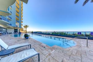 ein Pool mit Bänken und das Meer im Hintergrund in der Unterkunft Sterling Breeze 2304 in Panama City Beach