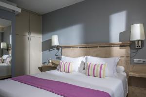a bedroom with a large bed with white sheets and pillows at Skajado Holiday Apartments in Stalís