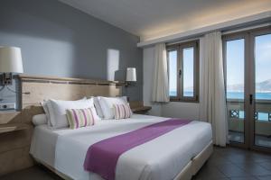a bedroom with a large bed with a large window at Skajado Holiday Apartments in Stalís