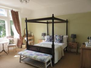 1 dormitorio con cama con dosel y silla en Ravenswood House B&B, en Fort William