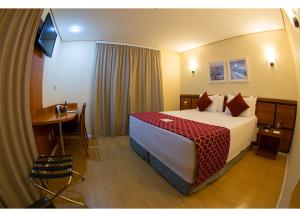 サンパウロにあるレーキス ブラジル ホテル エスコーラの大きなベッドとテーブルが備わるホテルルームです。
