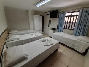 a room with three beds and a television in it at Pousada Damasco in Brasilia