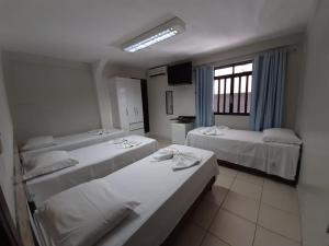 a hotel room with three beds and a window at Pousada Damasco in Brasilia