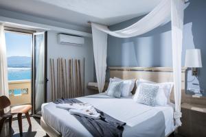 a bedroom with a white bed with a window at Skajado Holiday Apartments in Stalís