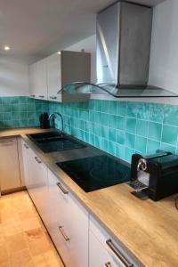 a kitchen with a sink and blue tile on the wall at Loft 3 pièces dans vieil Antibes in Antibes