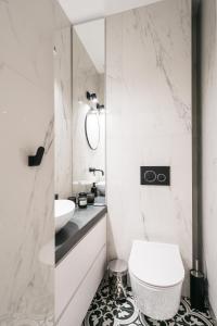 a white bathroom with a toilet and a sink at Papillon Apartment by LoftAffair in Kraków