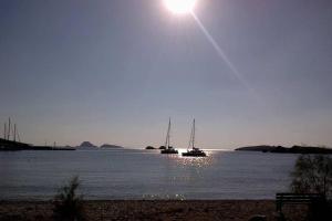 two boats in the water with the sun in the sky at Family house by the seaside of Karavostasis in Karavostasi