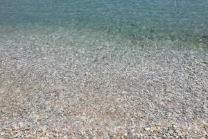 a close up of the water with rocks on a beach at Family house by the seaside of Karavostasis in Karavostasi
