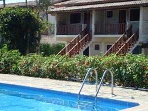 uma piscina em frente a um edifício com flores em Chalés Ancoradouro em Boraceia