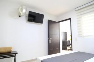 a bedroom with a bed and a tv on the wall at La Pera Hotel in Bucaramanga