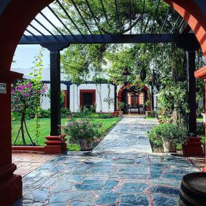 a stone patio with an archway with plants and flowers at Hotel El Farol in Parras de la Fuente