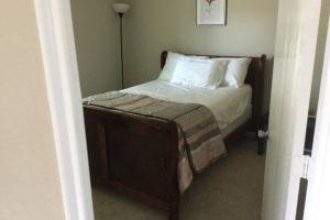 um pequeno quarto com uma cama com lençóis brancos e almofadas em House 8122 em Humble