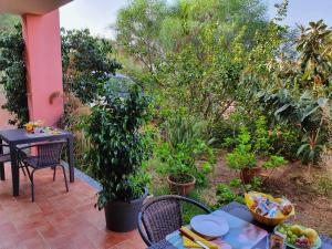 a patio with a table and chairs and trees at B&B I Colori di Chia in Chia