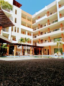 een groot wit gebouw met palmbomen ervoor bij Aurora Resort in Rincon de Guayabitos