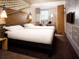 a hotel room with a large bed and a desk at ibis London City - Shoreditch in London