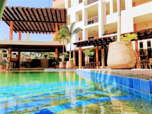 a swimming pool in front of a building at Aurora Resort in Rincon de Guayabitos