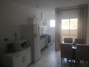 eine Küche mit einem Kühlschrank und einem Tisch mit einer Mikrowelle in der Unterkunft Ubatuba - Apto - Cond Sun Way - 1401 in Ubatuba