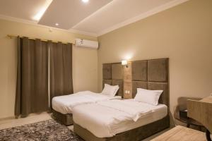 a bedroom with two beds with white sheets at فندق وفود فرع رفحاء in Rafha