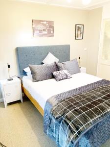 a bedroom with a large bed with a blue headboard at The Little Red Shed in Russell