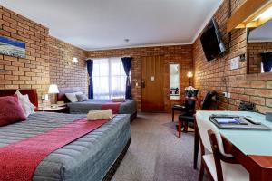 Jolly Swagman Motor Inn Euroa في اوروا: غرفه فندقيه بسرير واريكه