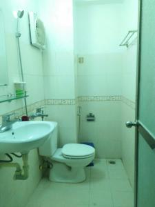 a white bathroom with a toilet and a sink at Song Châu Villa Quan Lạn in Quang Ninh